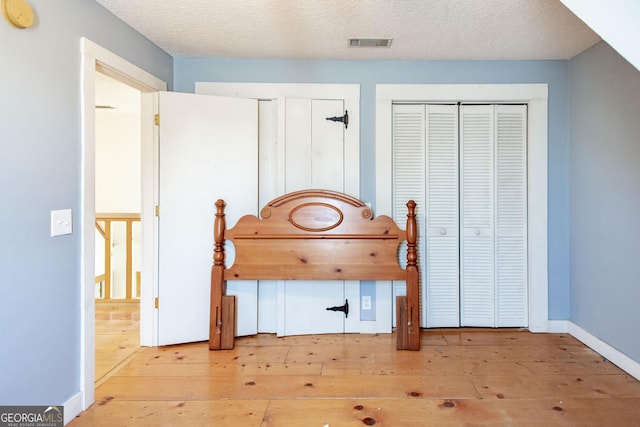 bedroom with baseboards, wood-type flooring, and visible vents