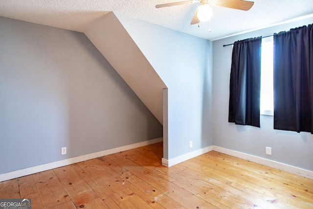 bonus room with a ceiling fan, a textured ceiling, vaulted ceiling, hardwood / wood-style flooring, and baseboards