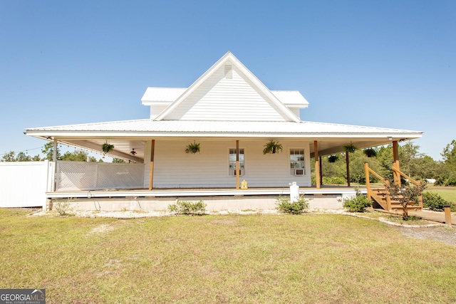 view of front of house with fence, metal roof, a porch, and a front lawn