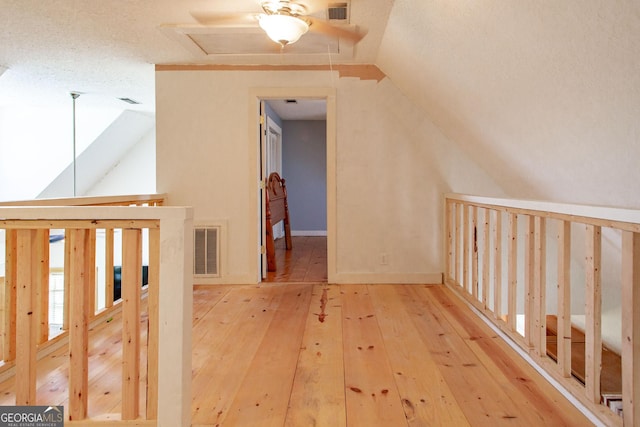 corridor featuring hardwood / wood-style flooring, visible vents, and lofted ceiling