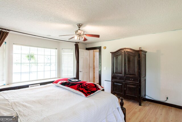 bedroom with a textured ceiling, light wood finished floors, and ceiling fan