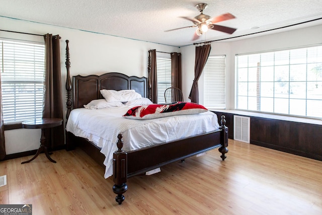 bedroom with visible vents, a textured ceiling, light wood-style floors, and a ceiling fan