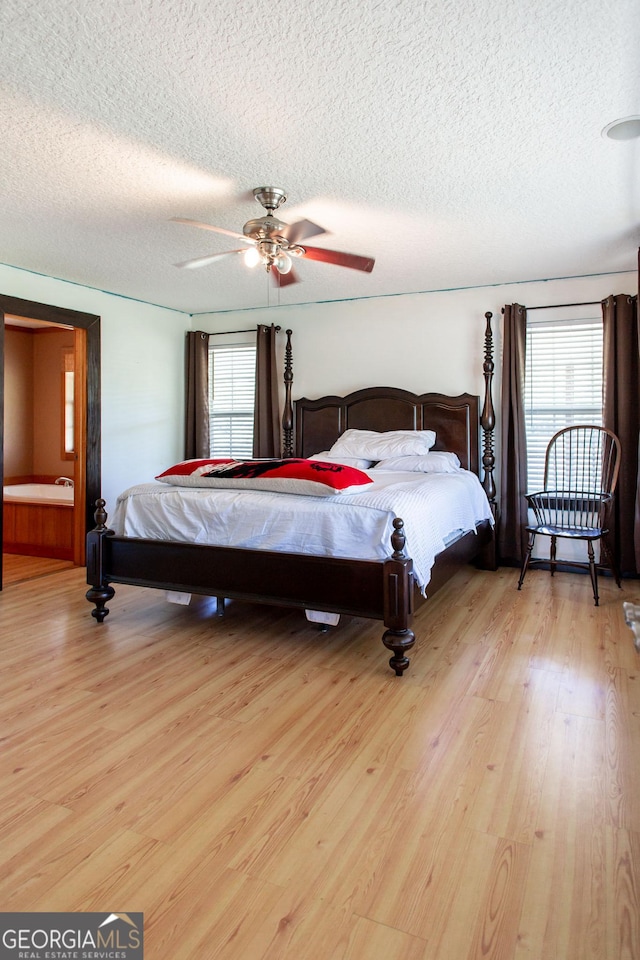 bedroom featuring a ceiling fan, a textured ceiling, multiple windows, and light wood finished floors