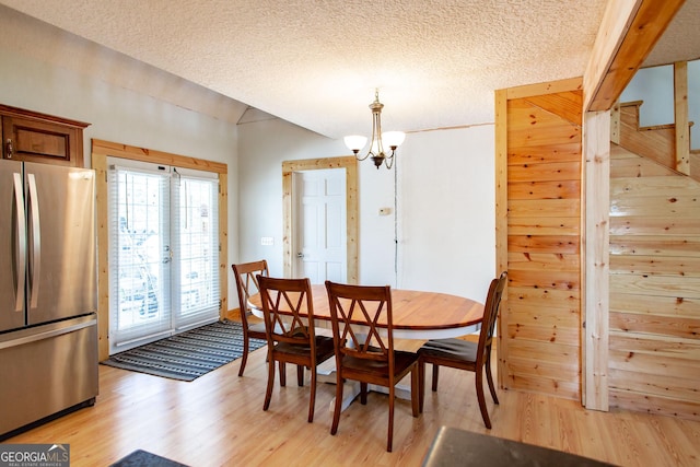 dining area with light wood-style floors, stairs, a textured ceiling, and a notable chandelier