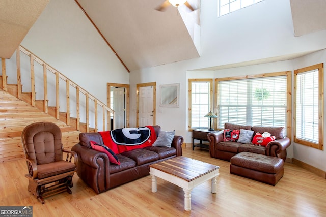 living area featuring high vaulted ceiling, stairs, wood finished floors, and a wealth of natural light