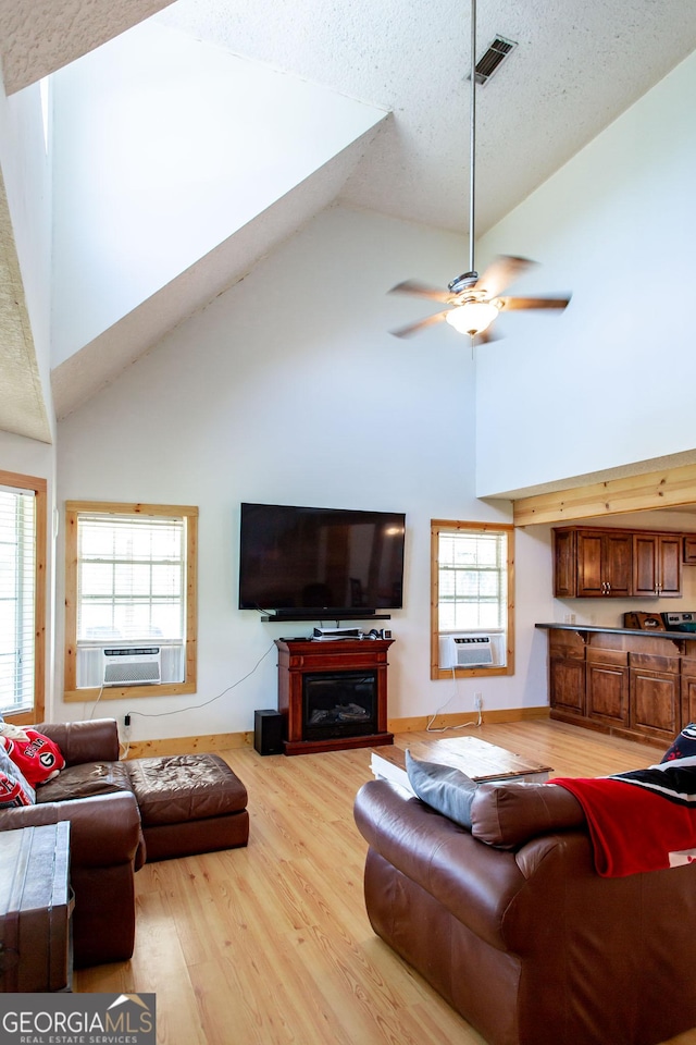 living room featuring cooling unit, high vaulted ceiling, ceiling fan, and light wood-style floors