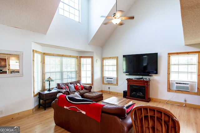 living area with wood finished floors, baseboards, ceiling fan, high vaulted ceiling, and cooling unit