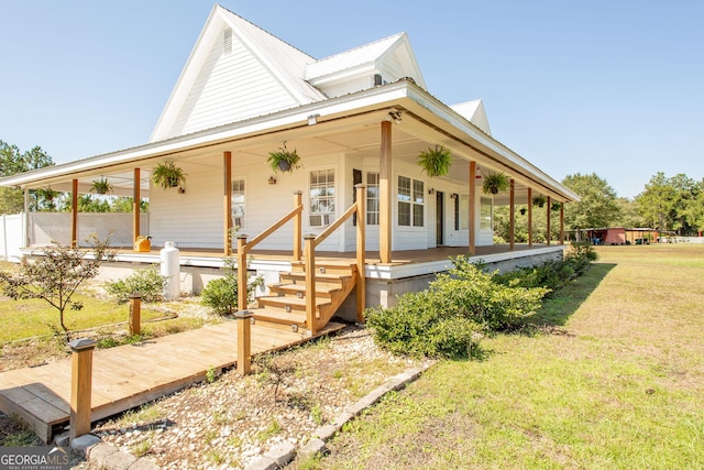 country-style home with covered porch, metal roof, and a front yard