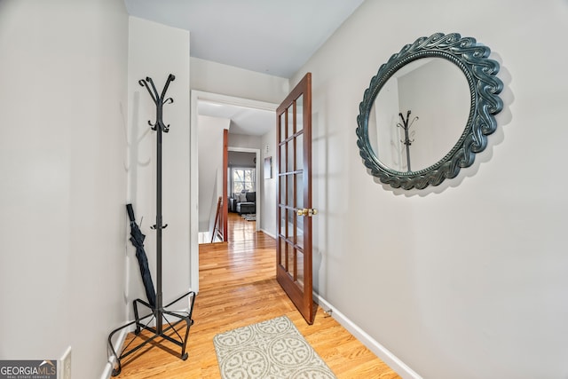 corridor with baseboards, french doors, and light wood finished floors