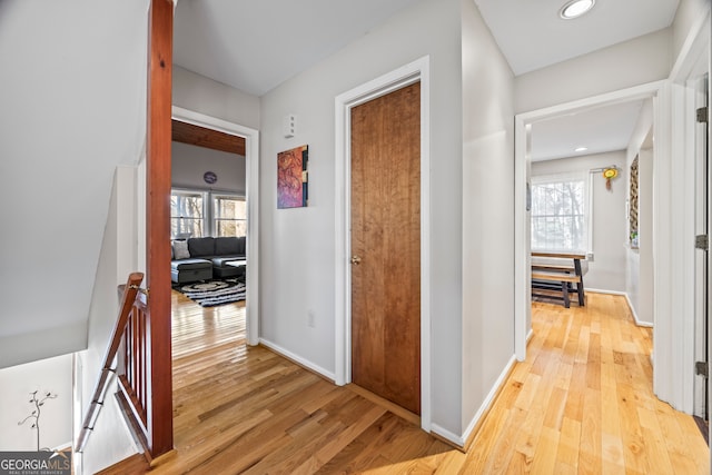 hallway with baseboards, recessed lighting, light wood-style flooring, and an upstairs landing