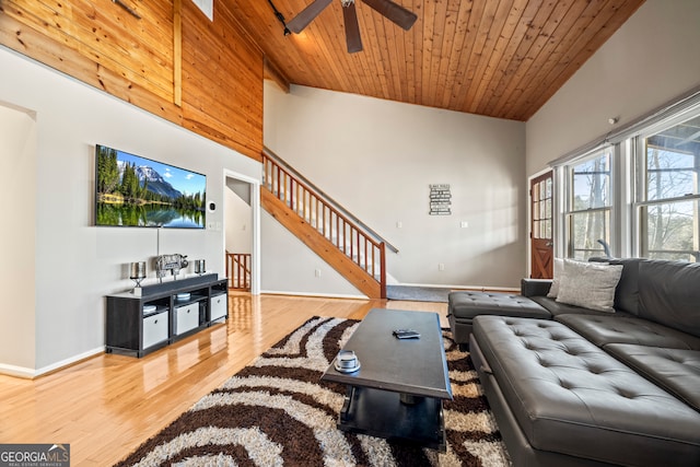 living area featuring a ceiling fan, baseboards, wooden ceiling, wood finished floors, and stairway