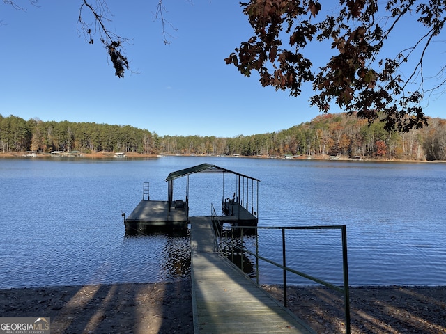 view of dock featuring a water view, boat lift, and a wooded view
