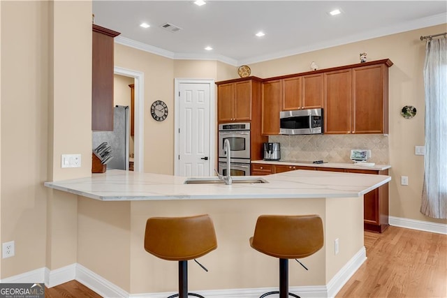 kitchen with visible vents, a peninsula, a breakfast bar, backsplash, and stainless steel appliances
