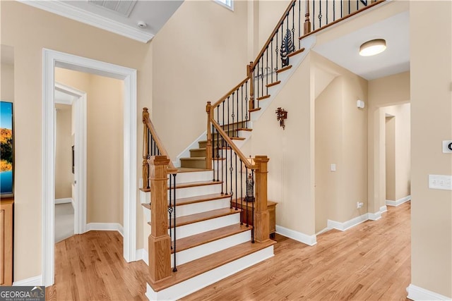 stairs featuring crown molding, baseboards, visible vents, and wood finished floors