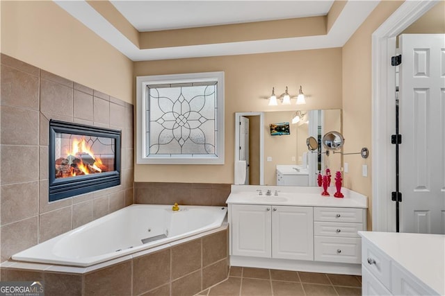 bathroom with vanity, a tile fireplace, tile patterned flooring, and a jetted tub