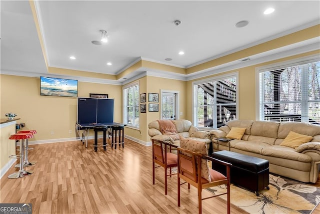 living room with light wood-style floors, recessed lighting, baseboards, a tray ceiling, and ornamental molding