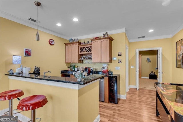 kitchen featuring crown molding, visible vents, light wood-style flooring, and a breakfast bar area