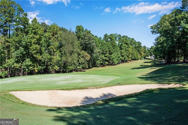 view of community with golf course view and a yard
