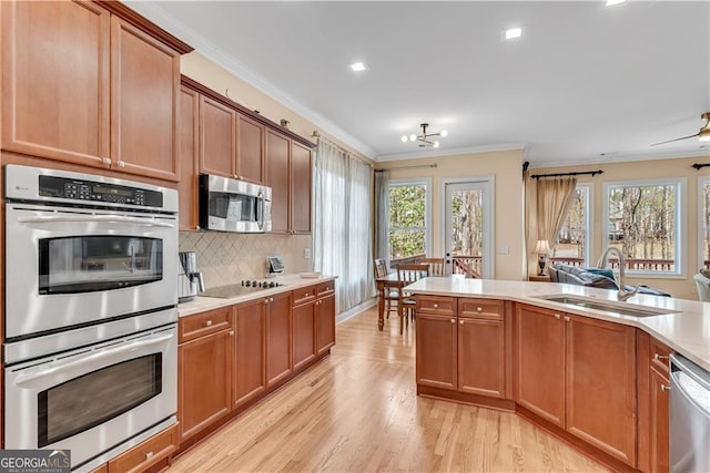 kitchen featuring ornamental molding, light wood-type flooring, light countertops, a sink, and stainless steel appliances