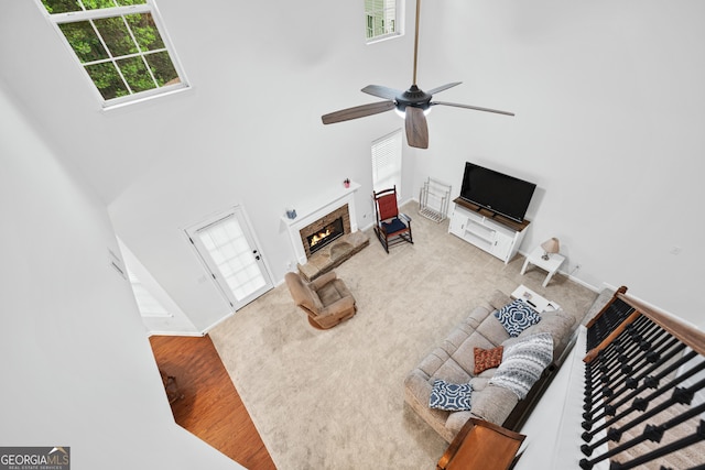 449 Highlands Loop, Woodstock, GA 30188 - living area featuring ceiling fan, a towering ceiling, wood finished floors, a warm lit fireplace, and baseboards