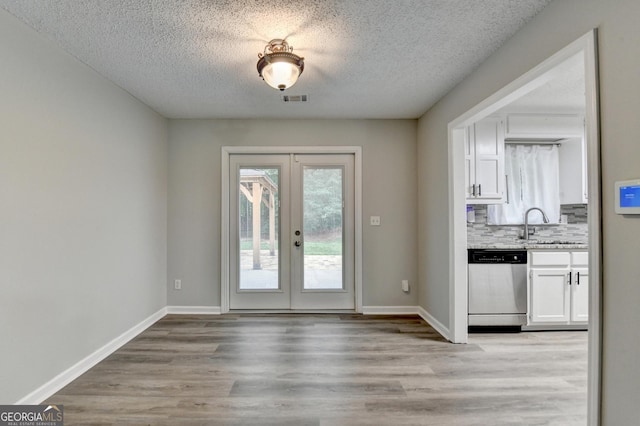 entryway featuring french doors, a textured ceiling, visible vents, light wood-type flooring, and a sink