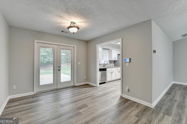doorway featuring french doors, a textured ceiling, visible vents, wood finished floors, and a sink