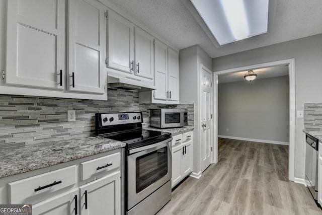 kitchen featuring appliances with stainless steel finishes, white cabinets, under cabinet range hood, and tasteful backsplash
