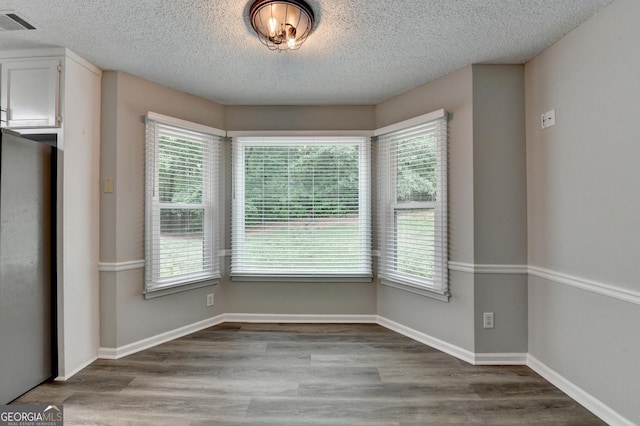 unfurnished dining area featuring visible vents, wood finished floors, and a wealth of natural light