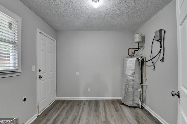 entrance foyer with baseboards, a textured ceiling, water heater, and wood finished floors