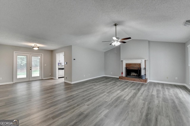 unfurnished living room featuring a brick fireplace, a textured ceiling, ceiling fan, and wood finished floors