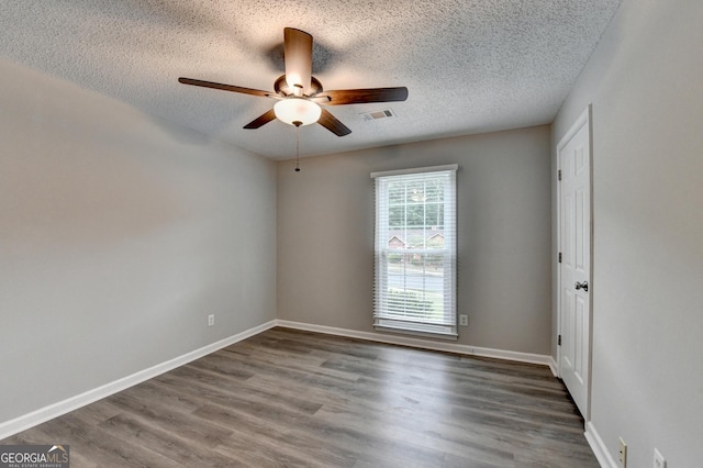 spare room featuring a textured ceiling, a ceiling fan, baseboards, wood finished floors, and visible vents