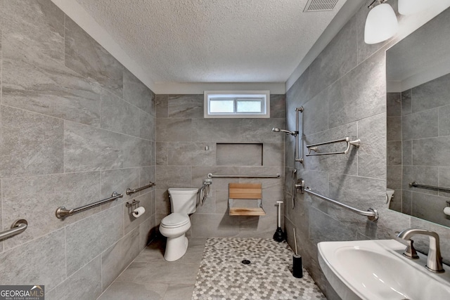 full bath featuring a sink, tile walls, a tile shower, and toilet
