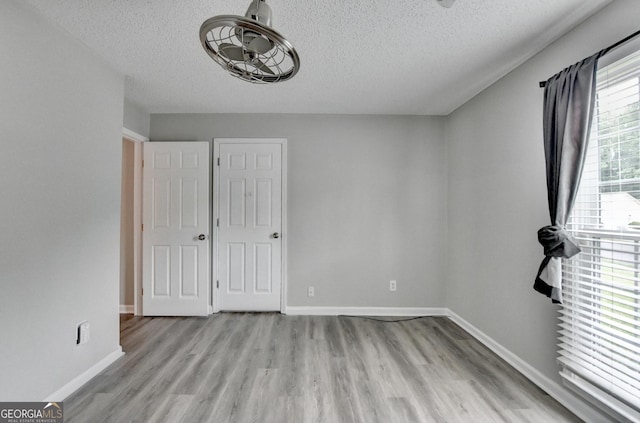 unfurnished bedroom featuring baseboards, a textured ceiling, and wood finished floors