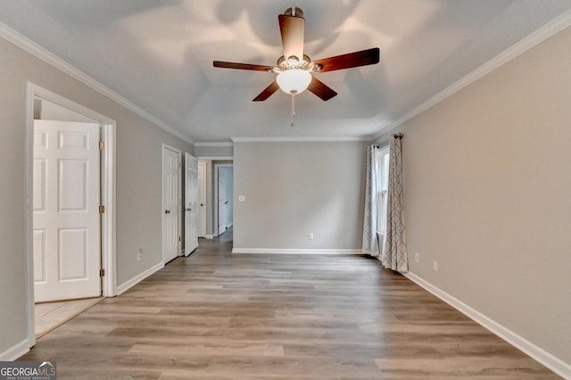 interior space with baseboards, ceiling fan, ornamental molding, and wood finished floors