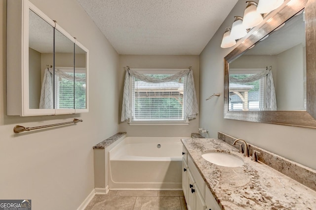 bathroom featuring a garden tub, a textured ceiling, a wealth of natural light, and vanity