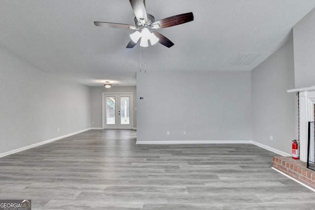 unfurnished living room with visible vents, wood finished floors, a fireplace, baseboards, and ceiling fan
