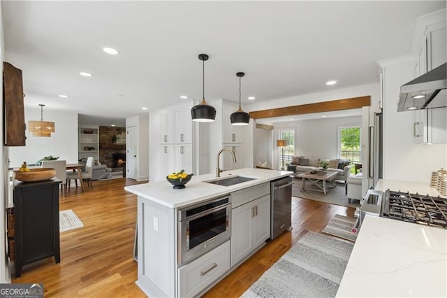 kitchen with pendant lighting, a center island with sink, a sink, open floor plan, and stainless steel appliances