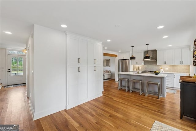kitchen featuring a sink, light countertops, white cabinetry, light wood-type flooring, and a kitchen bar