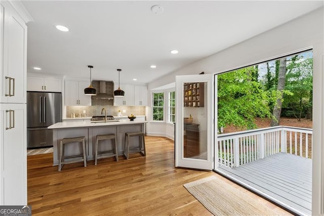 kitchen with a sink, light wood finished floors, light countertops, high end refrigerator, and white cabinetry