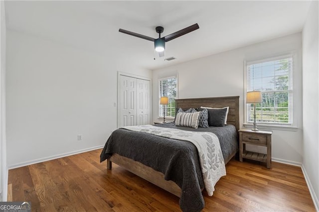 bedroom with baseboards, multiple windows, wood finished floors, and visible vents