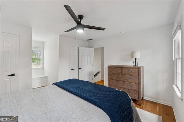 bedroom with visible vents, baseboards, ceiling fan, and wood finished floors