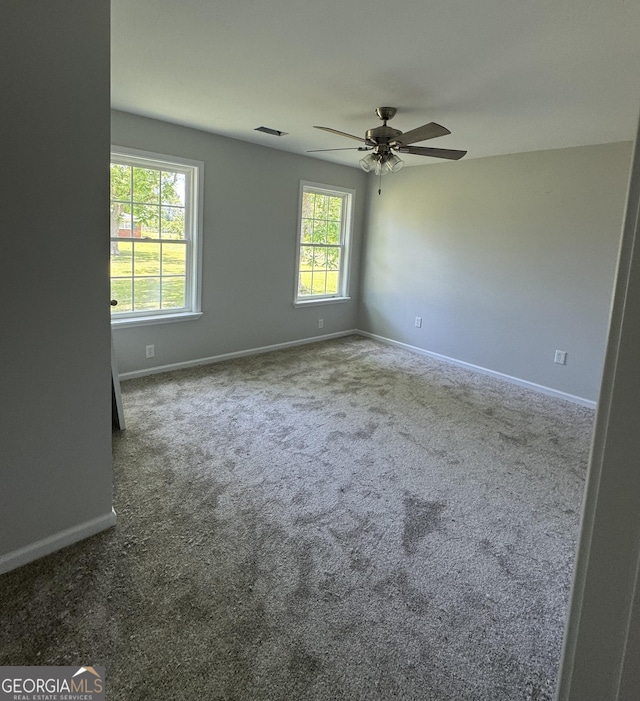 carpeted spare room featuring baseboards, a ceiling fan, and visible vents