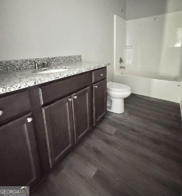 full bath featuring vanity, toilet, wood finished floors, and shower / tub combination