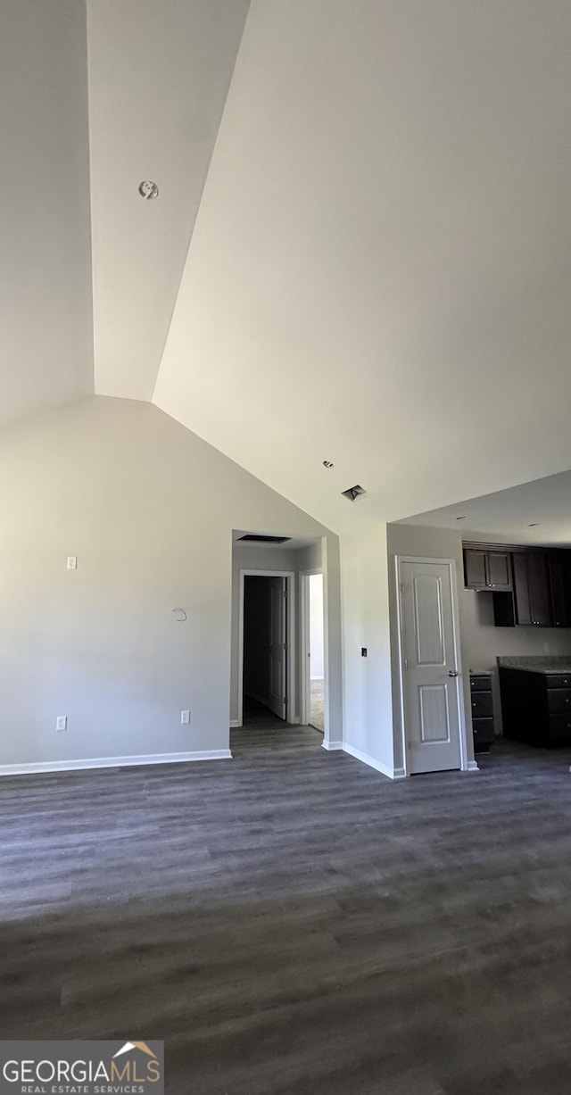 unfurnished living room with baseboards, visible vents, dark wood finished floors, and lofted ceiling