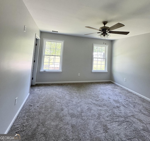 carpeted spare room featuring baseboards and a ceiling fan