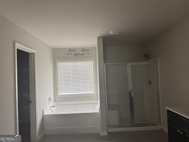 bathroom featuring a stall shower, baseboards, a bath, and vanity