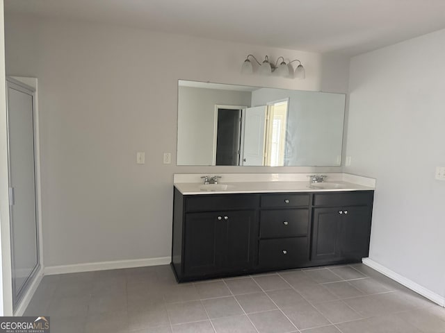 bathroom featuring a sink, baseboards, tile patterned flooring, and double vanity