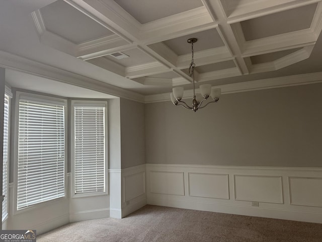 spare room with light colored carpet, beam ceiling, an inviting chandelier, ornamental molding, and coffered ceiling