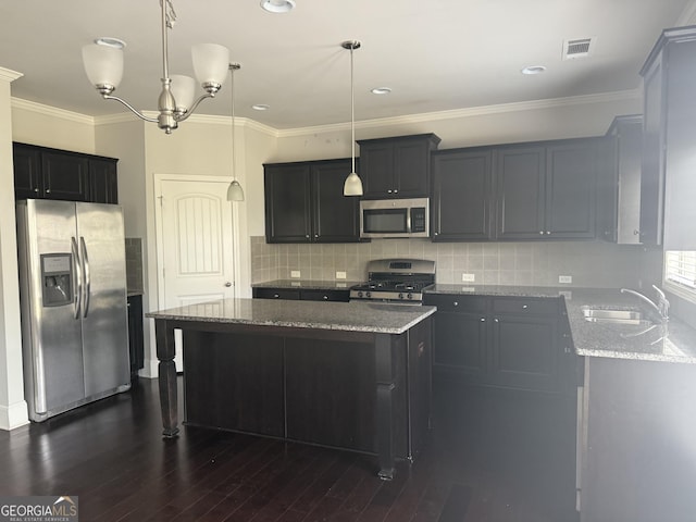 kitchen featuring appliances with stainless steel finishes, a sink, stone countertops, a center island, and visible vents