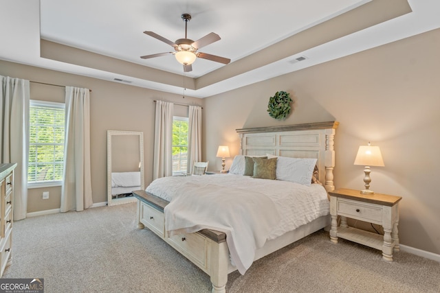 bedroom featuring visible vents, a raised ceiling, and light carpet